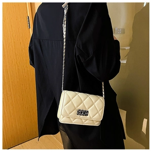 Close-up of beige quilted chain bag with gold metal buckle on a shoulder strap