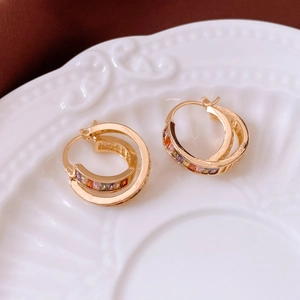 Close-up of gold-plated square cutout hoop earrings with inlaid colorful gemstones