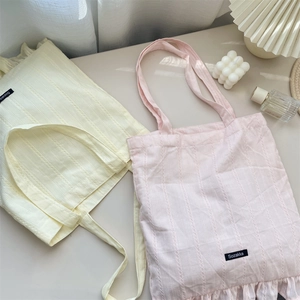 Detail shot of pastel canvas tote bags with vertical texture and ruffled edges decoration