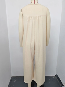 Close-up of beige sleeveless jumpsuit featuring textured knit fabric and back pleat detail