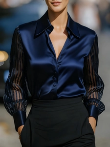 Detail of navy blue satin blouse featuring elegant semi-transparent striped chiffon sleeves