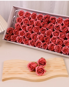 Detail shot of artificial pink soap roses on a wooden tray and in a gift box packaging