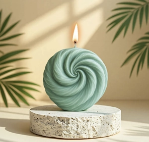 Detailed view of mint green spiral sphere candle lit on a natural stone pedestal
