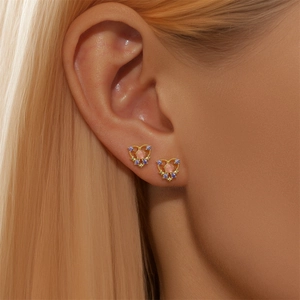 Close-up of gold stud earrings with pink heart stone and purple accents on female model