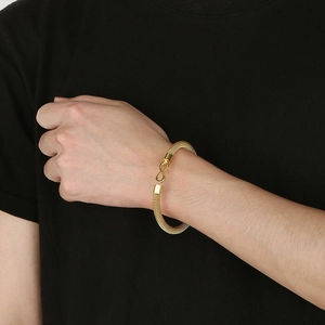 Detailed view of a gold mesh wristband featuring an infinity symbol clasp on a model