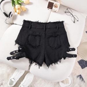 Detalle de shorts vaqueros negros con aberturas laterales y hebilla sobre tela blanca
