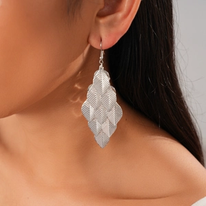 Macro detail of silver leaf tassel earrings with textured metallic finish on model