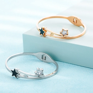 Detail of rose gold and silver star bangles with zircon inlay on blue display