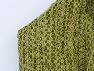 Detail of green knit hollow-out crochet texture with intricate woven patterns and mesh