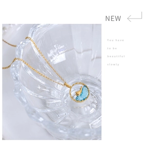 Makroaufnahme einer Goldkette mit blauem Edelsteinanhänger und Walflossen-Detail