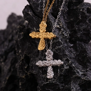 Macro shot of 18K gold and silver hammered texture cross pendants on black rock background