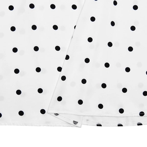 Close-up of hemline stitching on a white French-style summer dress with black polka dots