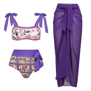 Three-piece purple floral bikini set with high-waisted bottoms and sheer long sarong skirt