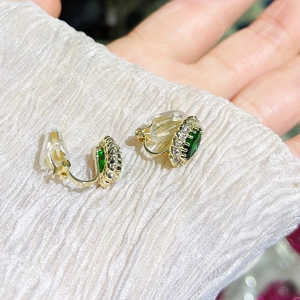 Elegante goldene Ohrclips mit ovalem grünem Edelstein und funkelnden Zirkonsteinen