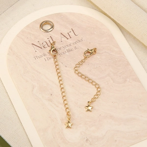 Detailed macro of two 18k gold-plated extension chains with lobster clasps and star pendants