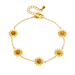 Bracciale palmo a fiori cavi dorati con centro ambra su uno sfondo bianco pulito
