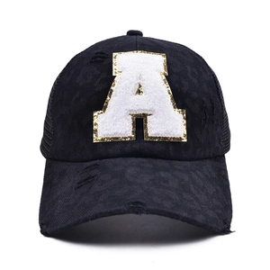 Close-up of vintage distressed black baseball cap with sequined letter A and mesh back