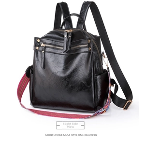 Detail of black faux leather backpack with colorful woven strap and golden zippers