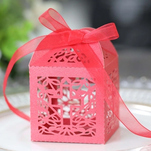 Macro shot of red laser-cut cross wedding favor box with a silk ribbon bow detail