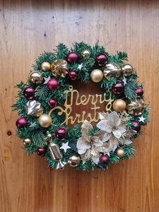 Detail of Christmas wreath featuring red gold balls, silk flowers and Merry Christmas sign