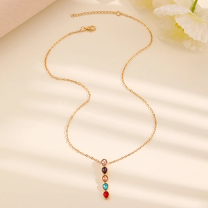 Close-up of golden alloy necklace featuring colorful gemstones on beige soft fabric