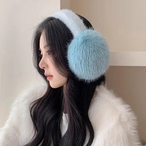 Plush light blue faux fur earmuffs with white headband worn by a model in winter style