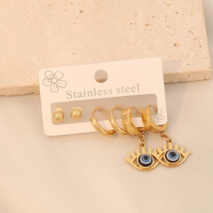 Detailed close-up of 3-pair gold stainless steel evil eye earring set on stone