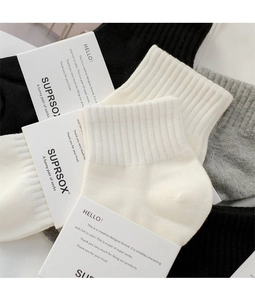 Dettaglio macro di calze sportive in cotone nero, bianco e grigio con polsini a coste fini