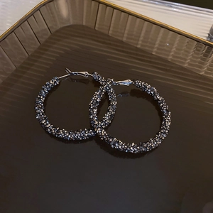 Macro detail of dark grey glitter geometric hoop earrings with sparkling crystal texture