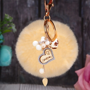 Détail du porte-clés pompon jaune avec cœur en bois et gravure I Love You