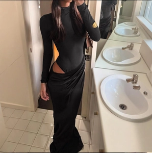 Detalle de un vestido largo negro ajustado con sexy abertura en la cintura y manga larga