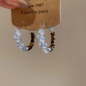 Detailed close-up of 18k gold plated hoop earrings with zircons and tiger eye beads