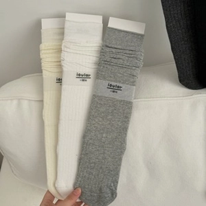 Detailed macro view of three cotton calf socks in beige, white, and grey with ribbed texture