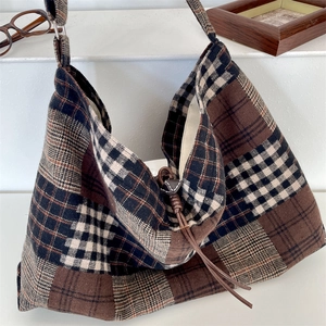 Dettaglio della borsa tote a quadri con cinturino in pelle marrone e trama in lana