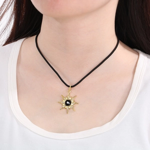 Close-up of gold starburst necklace with black gemstone and diamonds on a model