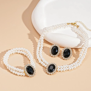 Detail of luxury pearl jewelry set featuring black oval stones and sparkling crystals