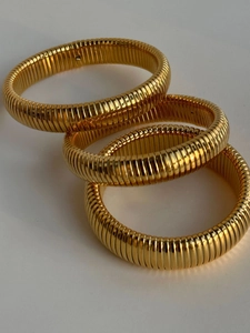 Close-up of three 18k gold plated Tubogas stretch bracelets with polished metallic texture