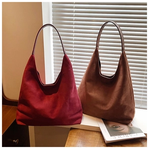 Detail of burgundy and brown suede hobo bags with soft matte texture and minimalist design