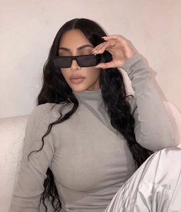 Detail of square black frame sunglasses with dark lenses on model face