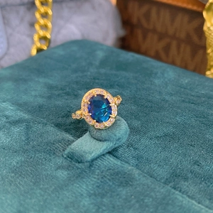 Macro detail of royal blue sapphire halo ring with gold setting on velvet stand
