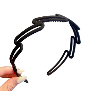 Flexible black wavy headband with non-slip teeth shown in hand for flexibility