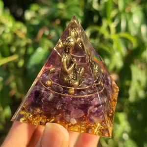 Detailed close-up of Orgone crystal pyramid with amethyst, golden Buddha and gold foil