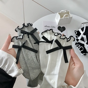 Close-up of grey and white socks with black bows and wavy lace edges for women