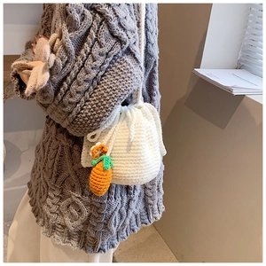 Detail of hand-knitted bucket bag with rabbit ears and cute carrot charm accessory