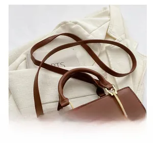 Close-up of brown textured leather bag with gold hardware and adjustable strap