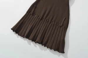 Detailed view of brown knitted pleated hem with ribbed texture and wavy edge finish