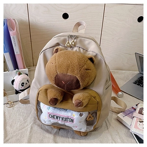 Detail of Capybara backpack with plush doll and bone pendant in student desk setting