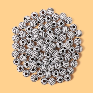Flat lay of white acrylic soccer beads with black patterns for DIY jewelry making