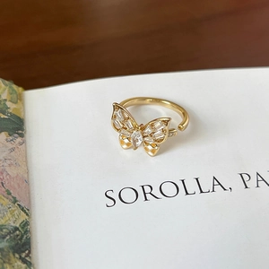 Macro shot of gold butterfly ring with sparkling zircon stones on an artistic book