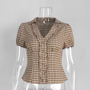 Detailed view of gingham plaid shirt featuring ruffle trim V-neck and button closure
